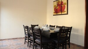 A dining area with a table set for four, surrounded by chairs, and a framed picture of apples on the wall. - Bungalows Yessy Tetos (Rincón de Guayabitos)