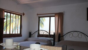 A room with two beds, a dining table with plates, cutlery, and a cup. - Bungalows Yessy Tetos (Rincón de Guayabitos)