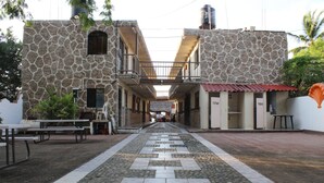 A courtyard with stone buildings, outdoor seating, and a tiled walkway. - Bungalows Yessy Tetos (Rincón de Guayabitos)