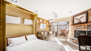A hotel room with a large bed, a sofa, a chair, a fireplace, and a balcony with a view. - Park City Ski In and Out Studio at Resort Center (Park City)