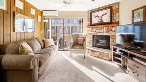 A cozy living room with a stone fireplace, a large TV, and a comfortable sofa. - Park City Ski In and Out Studio at Resort Center (Park City)