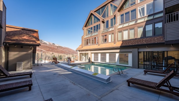 A modern building with a swimming pool, lounge chairs, and a mountain view. - Park City Ski In and Out Studio at Resort Center (Park City)