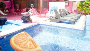 Un espace piscine aménagé avec des chaises longues, une table et des chaises.