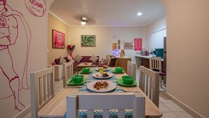 Un coin repas avec une table en bois dressée pour le repas, des bols verts et des assiettes.