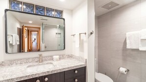 A bathroom with a large mirror, a sink, dark cabinets, a toilet, and a shower area. - Kayenta II 16 3 Bedroom/3 Bathroom Slopeside (Mountain Village)
