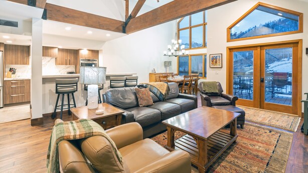 A spacious living area with a high ceiling, a dining area, and a kitchen.