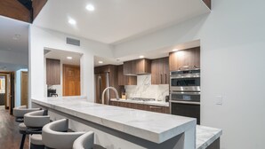 A modern kitchen with a marble countertop, stainless steel appliances, and wooden cabinets.