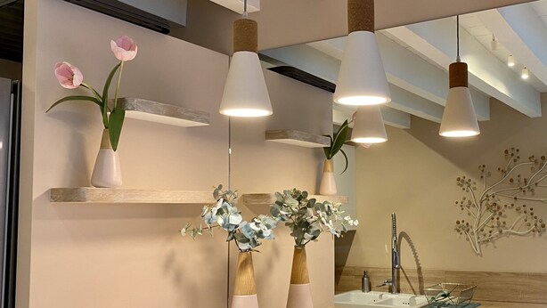 Une cuisine moderne avec des luminaires suspendus, un plan de travail en bois et un grand miroir.