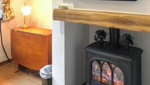 A living room with a TV mounted on the wall, a wooden cabinet, a lamp, and a fireplace with decorative items. - 2 bedroom accommodation in Ambleside (Ambleside)