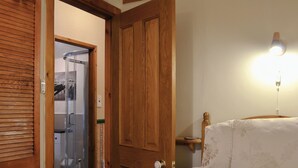 A hotel room with a wooden door, a bed with floral bedding, a bedside table, and a wall-mounted light fixture. - 2 bedroom accommodation in Ambleside (Ambleside)
