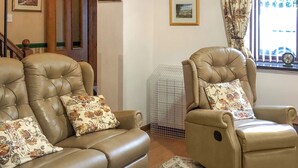 A living room with two leather armchairs, a standing lamp, and a window with curtains. - 2 bedroom accommodation in Ambleside (Ambleside)