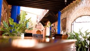 A dining area with a table, chairs, and potted plants. - Riad Mellado by Grupo Afekto (Guanajuato)