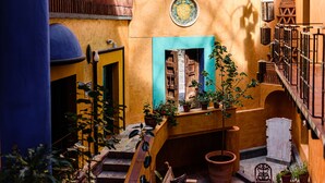 A courtyard with a wooden staircase, potted plants, and a tiled floor. - Riad Mellado by Grupo Afekto (Guanajuato)