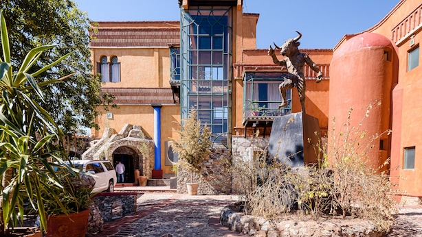 A courtyard with a statue, stone walls, and a building with a blue window. - Riad Mellado by Grupo Afekto (Guanajuato)