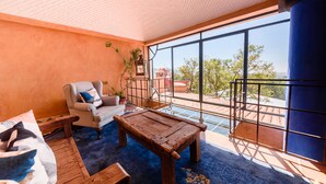 A room with a large window, a wooden table, a chair, and a sofa. - Riad Mellado by Grupo Afekto (Guanajuato)