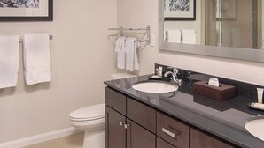 A bathroom with two sinks, a toilet, and a large mirror.