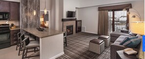 Cozy living space with a fireplace, sofa, and ottomans, plus a kitchen area with microwave and knife block.