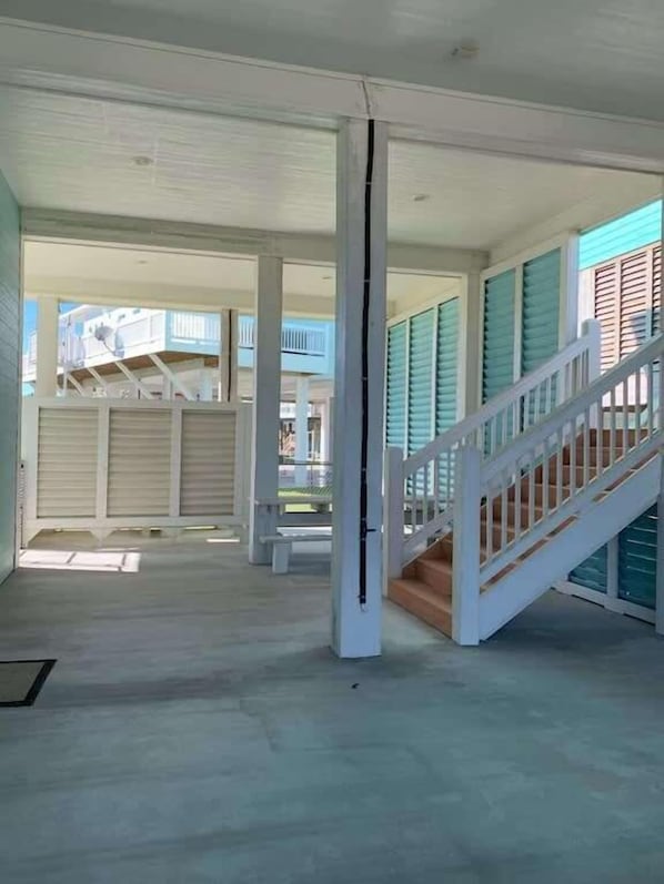 A spacious interior with a staircase leading to an upper level, large windows, and a view of the outside.