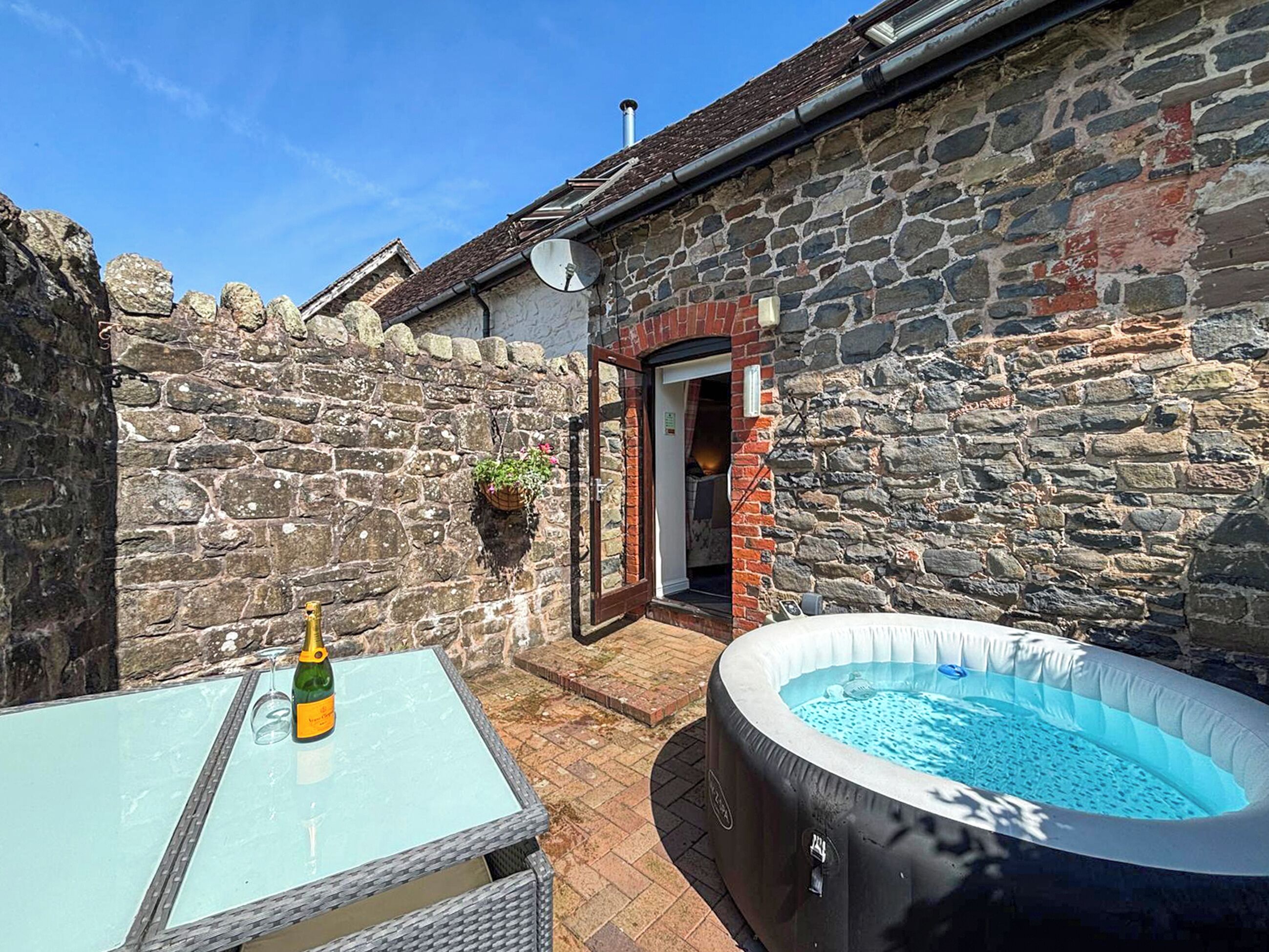 Ein Steinhaus mit einem Glastisch und einer Whirlpool-Badewanne.