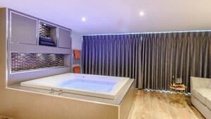 Une salle de bain moderne avec une grande baignoire, un plancher en bois et une étagère intégrée où sont rangées les serviettes.
