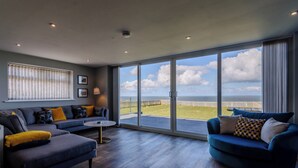 Un salon spacieux doté d’une grande porte-fenêtre coulissante donnant sur un balcon avec vue sur la mer.