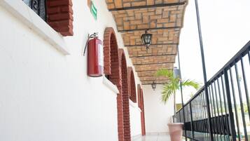Un pasillo cubierto con suelo de baldosas, arcos de ladrillo, un extintor y una planta en maceta.