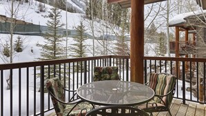 A wooden deck with a metal table and two chairs, overlooking a snowy mountain landscape. - Outpost: Grand View 5230 - Incredible Teton Views! (Jackson)
