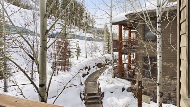A wooden cabin with a stone foundation, a wooden deck, and a snow-covered pathway leading to the entrance. - Outpost: Grand View 5230 - Incredible Teton Views! (Jackson)
