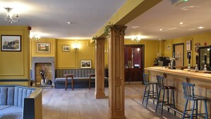 Eine Bar mit Hockern, einem Kamin und gerahmten Bildern an der Wand.