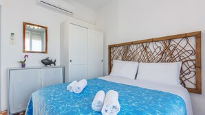Una camera d'albergo con un letto, un comodino, uno specchio, un armadio e un elemento decorativo a parete.