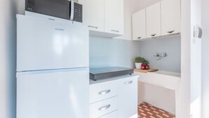 Una cucina compatta con un frigorifero bianco, un forno a microonde e un piccolo piano di lavoro.