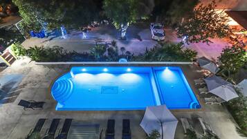 Alberca al aire libre, sombrillas en la alberca y camastros