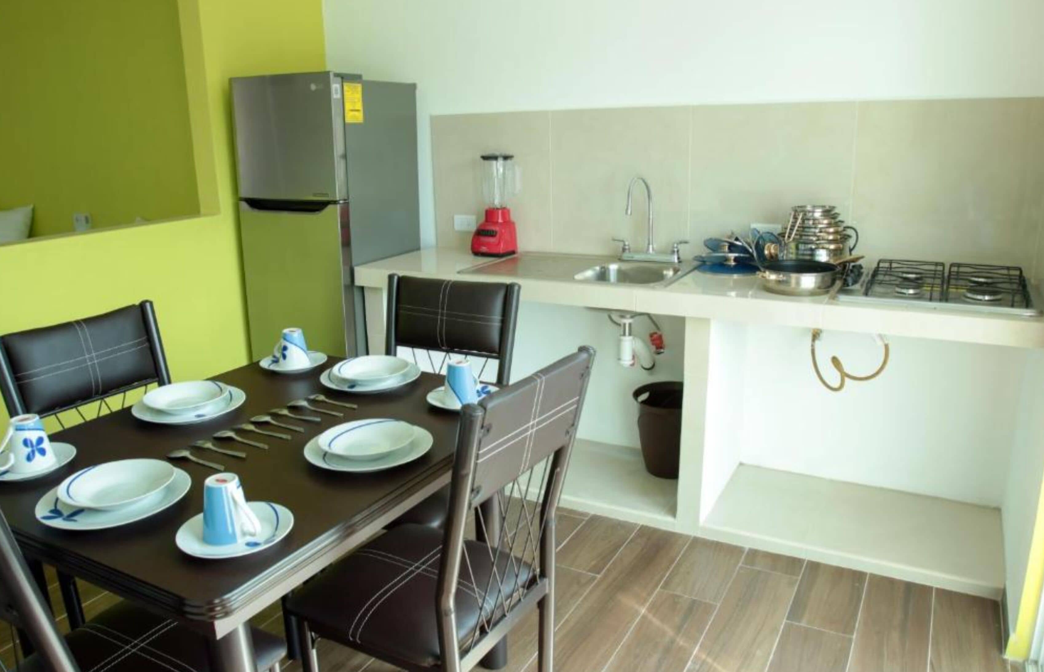 Cocina compacta con comedor, equipada con refrigerador, licuadora, pileta y estufa.