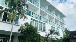 Un hotel moderno de varios pisos con balcones, ventanas amplias y abundante vegetación.