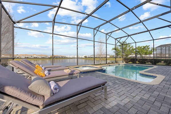 Una piscina exterior cubierta con sillones de descanso y un jacuzzi.