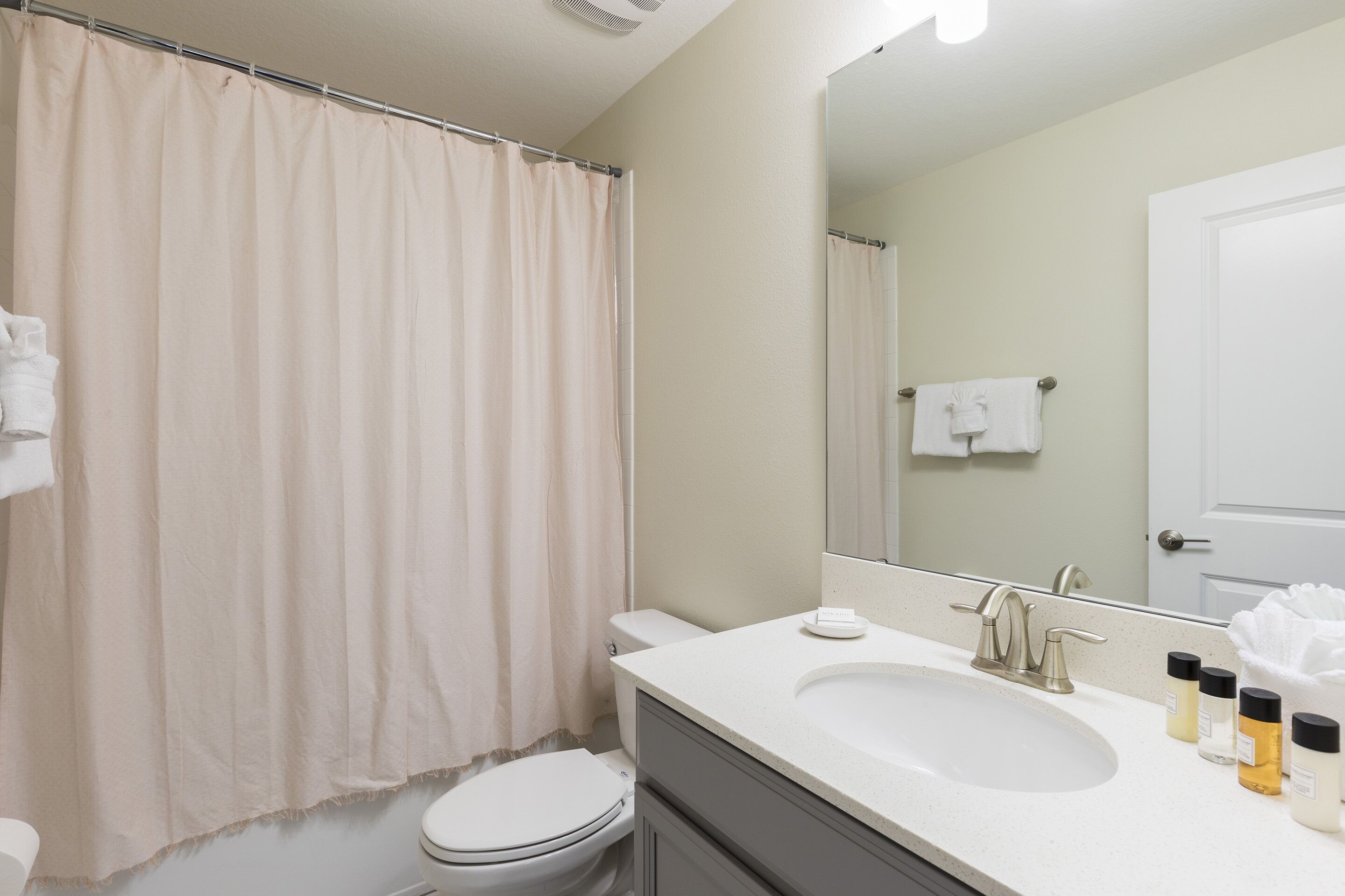 A bathroom with a toilet, sink, and shower curtain.