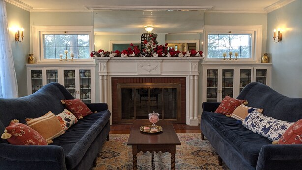 A living room with two dark blue sofas, a wooden coffee table, a fireplace, and a decorative mantelpiece.