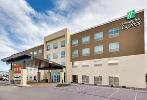 A Holiday Inn Express building with a covered entrance, multiple windows, and a parking lot with handicapped spaces. - Holiday Inn Express Kermit By IHG (Kermit)