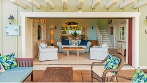 An open-plan living area with a sofa set, a coffee table, and wicker chairs. - Kahalu’u Surf and Snorkel Beachfront Paradise, with Hot Tub (Kailua-Kona)