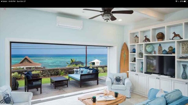 A spacious living area with a large sliding glass door leading to a balcony overlooking the ocean. - Kahalu’u Surf and Snorkel Beachfront Paradise, with Hot Tub (Kailua-Kona)