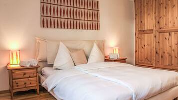 Ein Schlafzimmer mit einem großen Bett, zwei Nachttischen inklusive Lampen, einem Holzschrank und einem an der Wand befestigten Kunstwerk.