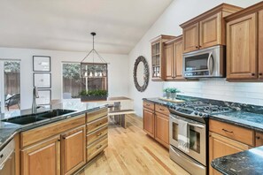 A kitchen with wooden cabinets, a stainless steel range, and a black countertop. - Exceptional Luxury - Walk to Downtown - Hot Tub - Outdoor Living (Bend)
