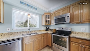 Enjoy cooking in this well-equipped kitchen with a granite countertop, stainless steel appliances, and a window with blinds.