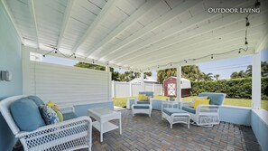 Relax in a serene outdoor space with a brick floor, wicker chairs, and a small table.