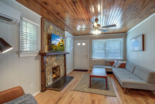 A living room with a stone fireplace, wooden ceiling, and a sofa.