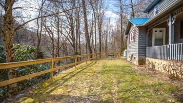 A wooden deck leading to a house with a stone foundation and a blue roof.