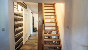 Un couloir étroit avec une échelle en bois menant à un escalier.