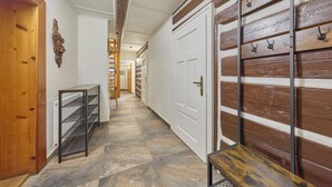 Un couloir avec une porte en bois, un présentoir en métal et un banc.