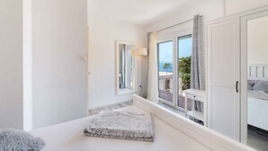 Un dormitorio con un ventanal grande, una cama, un armario y vistas al exterior.