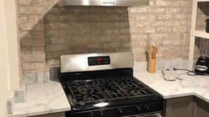 A kitchen with a stainless steel stove, oven, and a range hood above the stove. - Cozy Furnished Apartment (New Orleans)